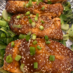 Oven-roasted miso glazed salmon fillet topped with sesame seeds, green onions, and cilantro, served with sautéed bok choy.