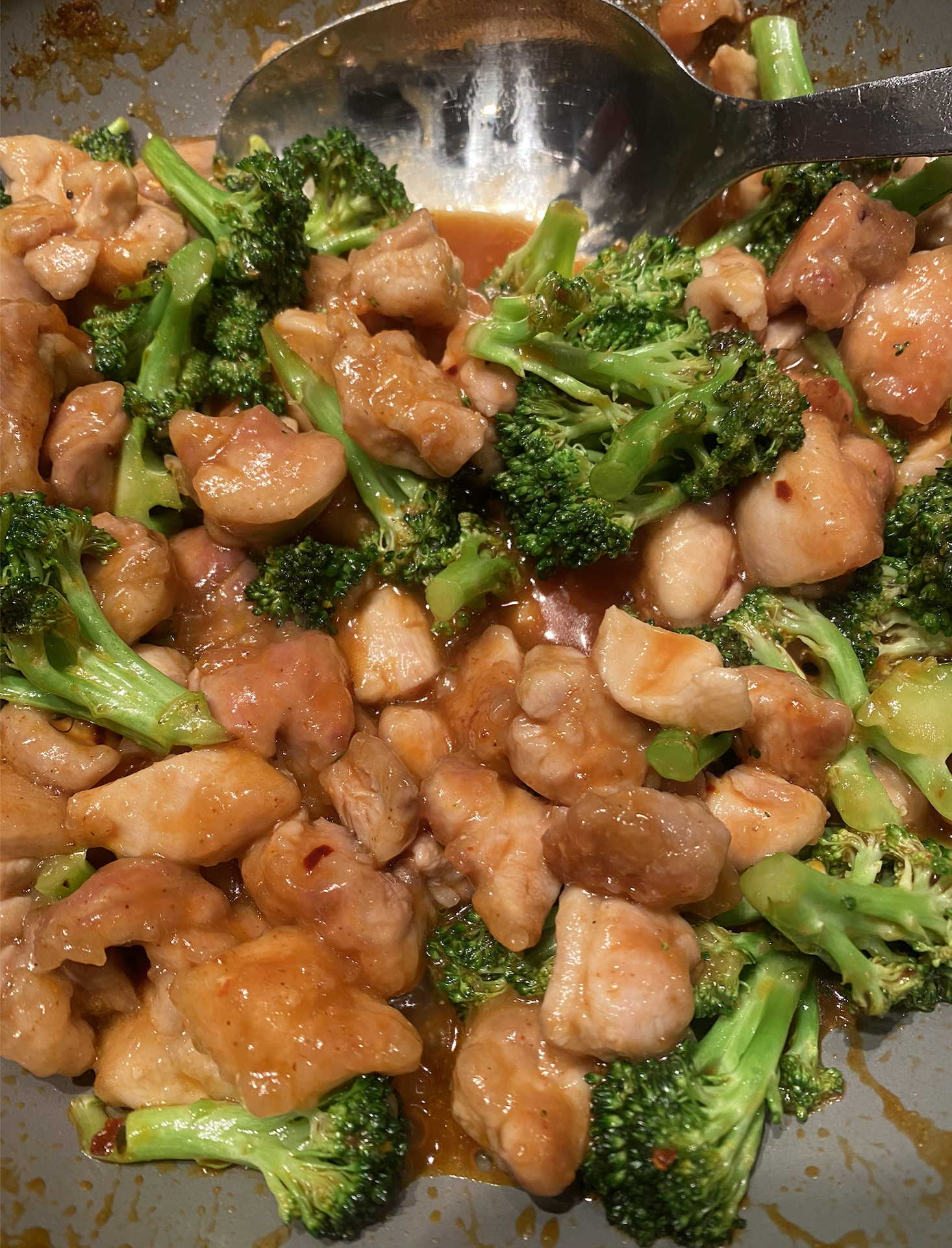 Bowl of orange chicken stir fry with broccoli, topped with sesame seeds and served over cauliflower rice.