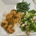 Sautéed shrimp and yellow tomatoes in a buttery garlic sauce, garnished with fresh basil and served in a white skillet