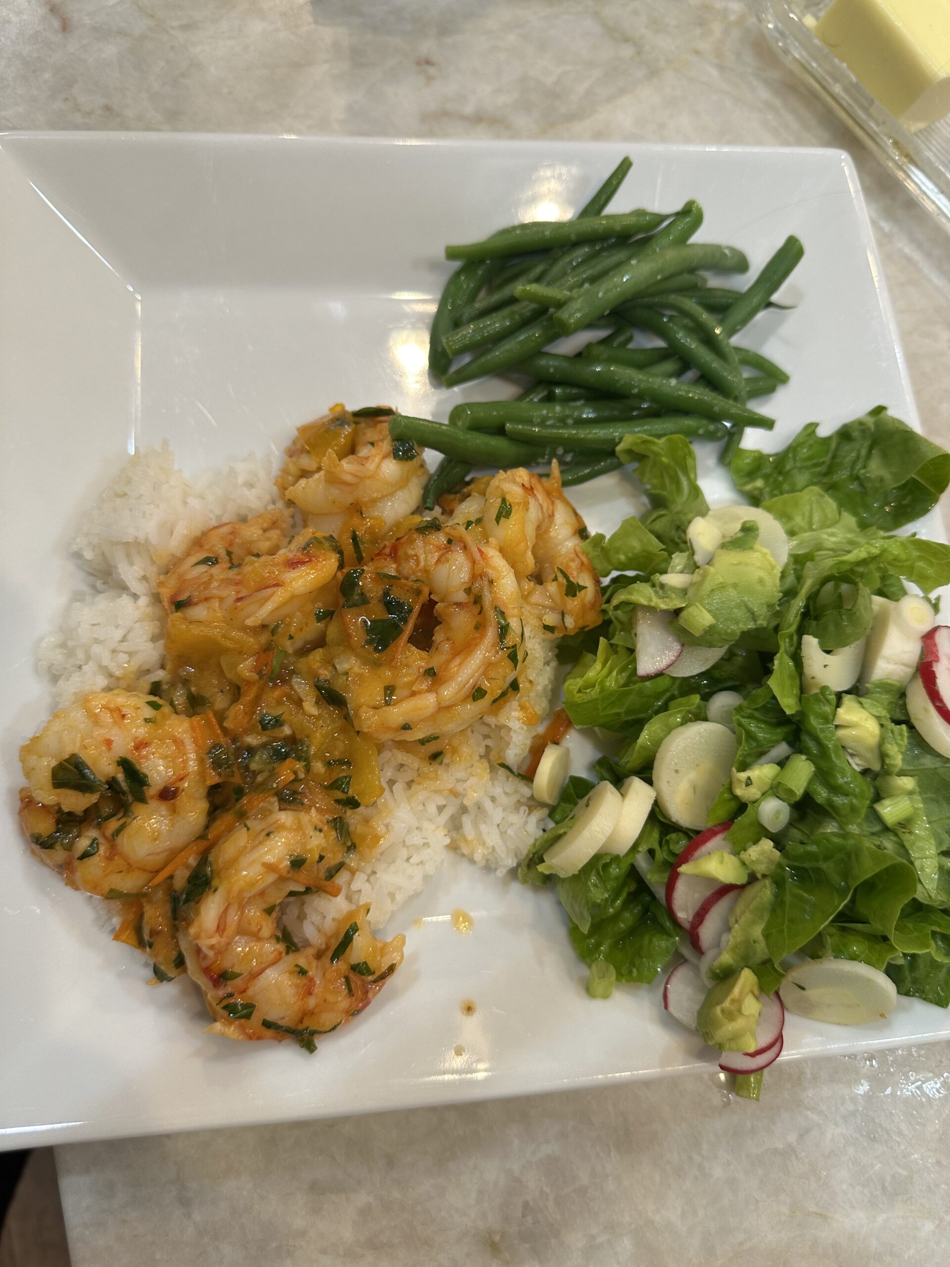 Sautéed shrimp and yellow tomatoes in a buttery garlic sauce, garnished with fresh basil and served in a white skillet