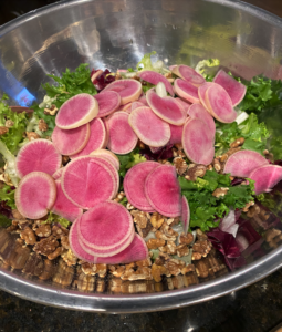 Colorful chicories salad with wheat berries, radishes, and toasted walnuts on a serving platter.