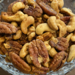 Bowl of festive mixed nuts with sweet and spicy seasoning, perfect for holiday snacking.