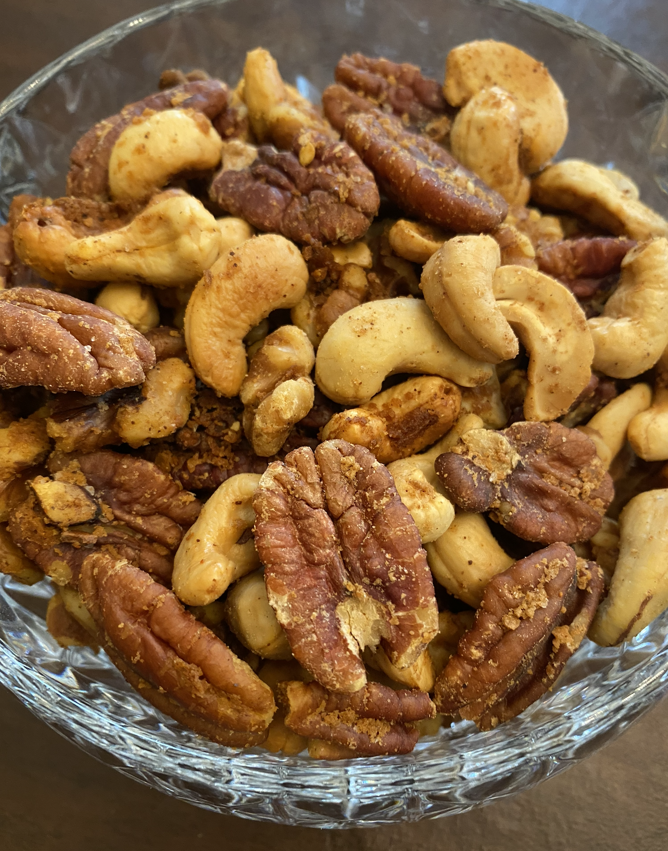 Bowl of festive mixed nuts with sweet and spicy seasoning, perfect for holiday snacking.