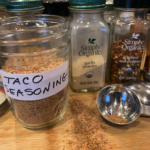 Homemade taco seasoning blend in a glass jar with measuring spoons