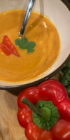 Creamy roasted red pepper soup with citrus and cashew cream in a white bowl.