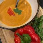 Creamy roasted red pepper soup with citrus and cashew cream in a white bowl.