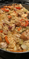 Traditional Spanish paella with chicken, shrimp, sausage, and saffron rice in a large skillet.
