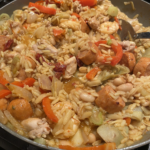 Traditional Spanish paella with chicken, shrimp, sausage, and saffron rice in a large skillet.