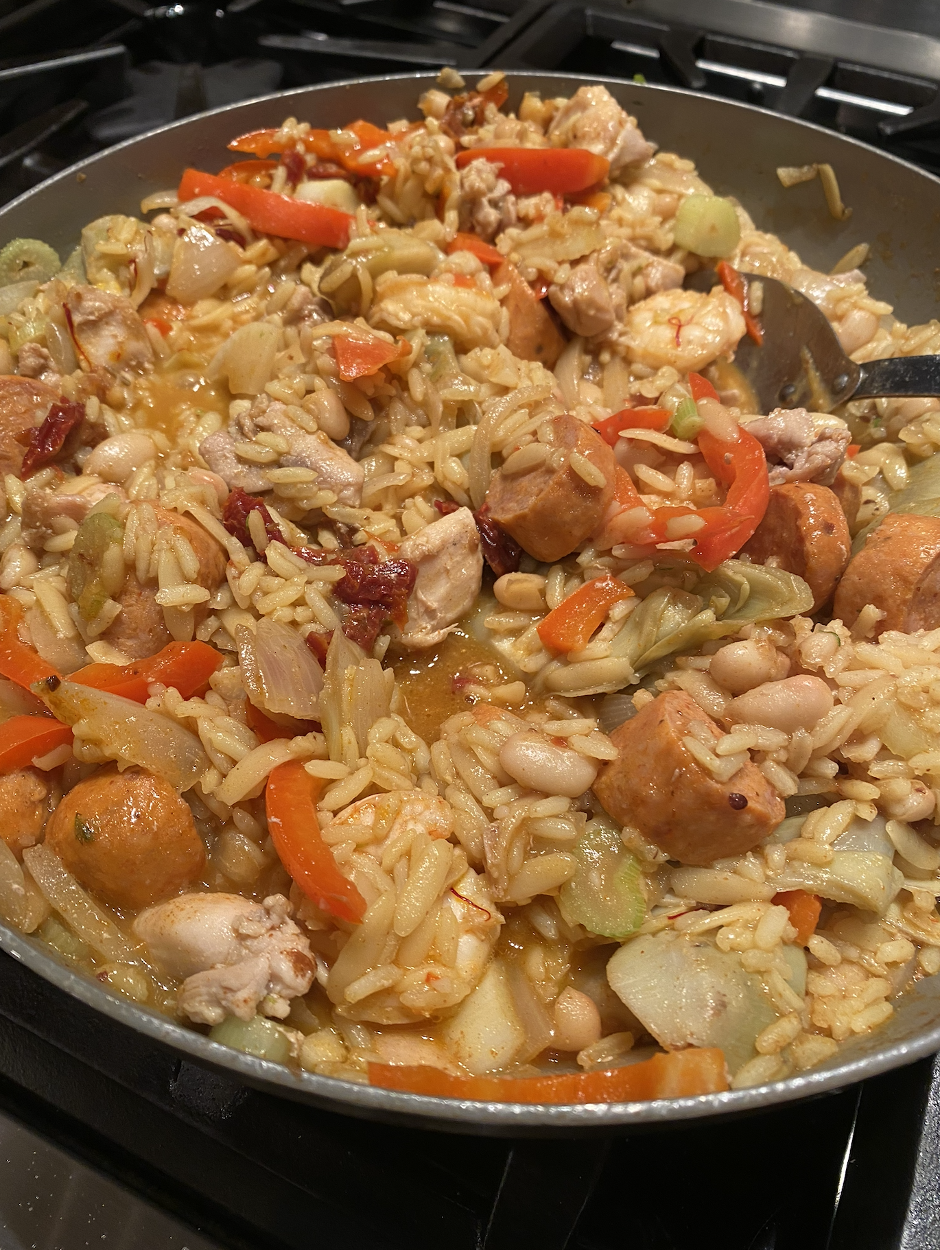 Traditional Spanish paella with chicken, shrimp, sausage, and saffron rice in a large skillet.